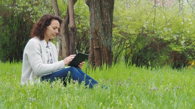Girl in the park with a tablet.