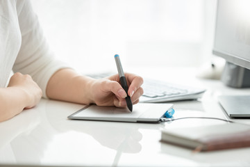 Closeup image of female hand drawing with stylus on graphic tablet