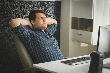 Toned portrait of young hipster man relaxing in big leather chair at home office