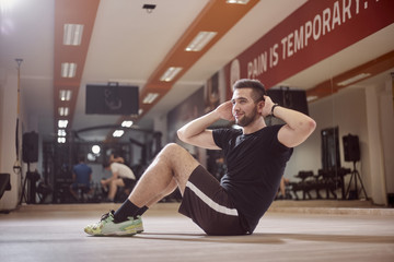 one young man, ordinary average man, exercise abs, sideways, sitting on floor, in gym....