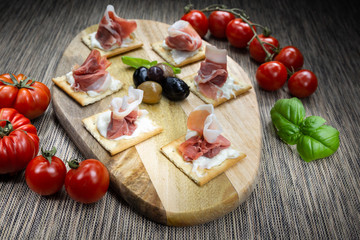 An appetizer of Italian ham, artisan stracchino and olives from Puglia (Italy). It is a very tasty typical appetizer.