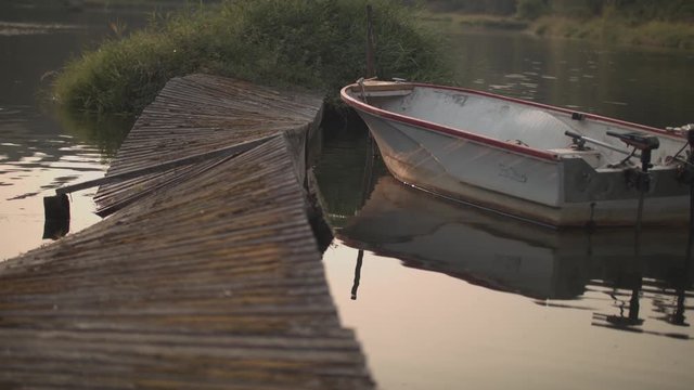 Handheld footage of a worn down dock and a motor boat on a calm lake.  Shot on a Blackmagic Ursa Mini Pro 4.6k with a Canon FD 70-210mm f/4.