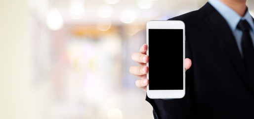 Businessman hand holding smartphone with blank on screen display over blur background, business...