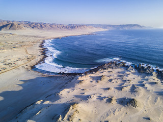 "Las Tortolas" beach at Atacama Desert with the last rays coming from the Sun in an aerial view from a drone