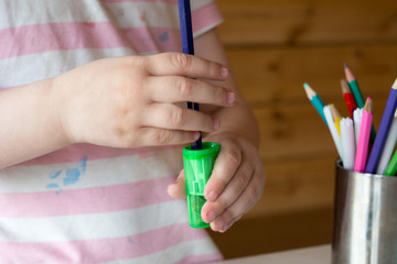 child sharpens colored pencils