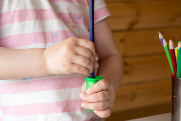 child sharpens colored pencils