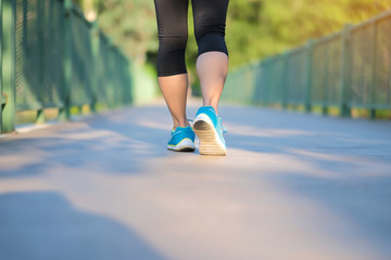 young fitness woman legs walking in the park outdoor, female runner running on the road outside, asian girl jogging and exercise on footpath in sunlight morning. healthcare and well being concepts