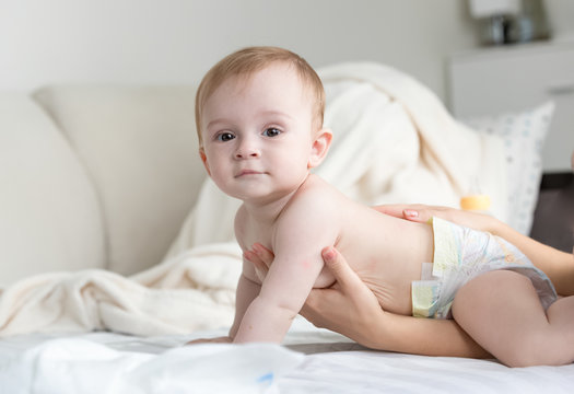 Portrait of adorable baby boy in diapers craling on bed at bedroom