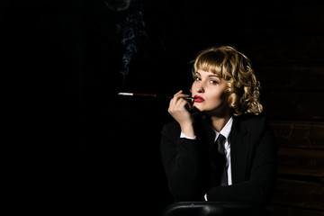 Fototapeta premium businesswoman with cigarette on a dark background, stylized retro portrait