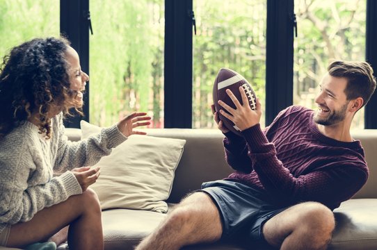 Young couple watching american football at home