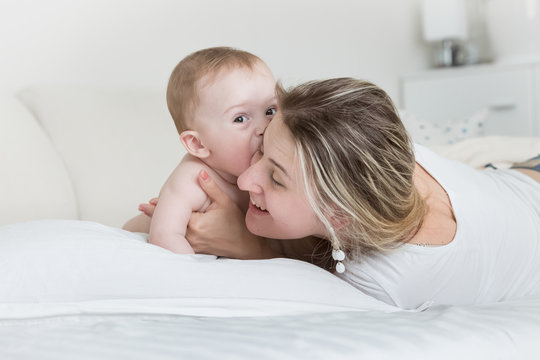 Portrait of happy smiling baby boy with mother on bed