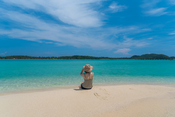 Fototapeta na wymiar A Asian woman relaxing on beautiful beach Koh Kham island ,Trad,Thailand with blue cloud sky background