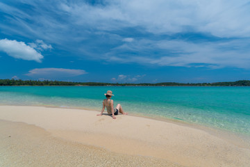 A Asian woman relaxing on beautiful beach Koh Kham island ,Trad,Thailand with blue cloud sky background