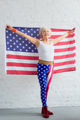 happy senior sportswoman holding american flag and smiling at camera