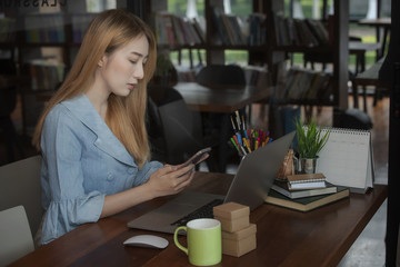 businesswoman using smartphone while sitting and working at her desk in modern office