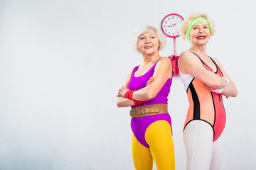 low angle view of happy senior sportswomen standing with crossed arms and smiling at camera