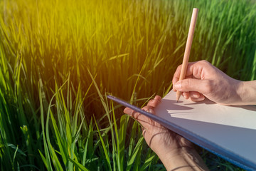 Woman hand holding a pencil on a notebook. Concept for agriculture