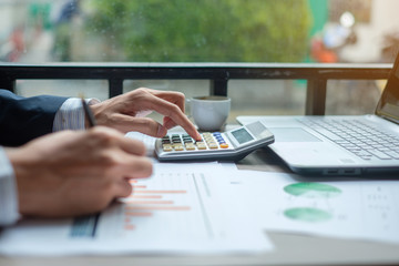 Businessman using calculator for analysis maketing plan, Accountant calculate financial report, computer with graph chart.  Business, Finance and Accounting concepts