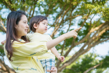 Closeup asian mother pointing her finger and tell her son to look in park view textured background