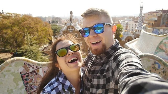 Travel couple happy talking selfie self-portrait with smartphone in Park Guell, Barcelona, Spain