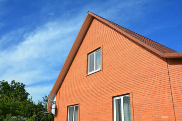 Modern red brick house construction. Brick house facade building with metal roof.