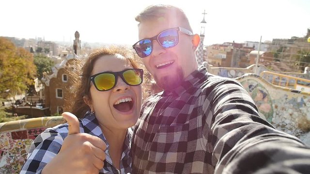 Travel couple happy talking selfie self-portrait with smartphone in Park Guell, Barcelona, Spain