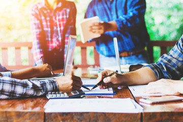 business partners hands using pen over document with their colleagues working on background