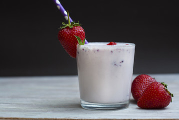 Milk Cocktail Shake Drink with Srawberry. homemade Fruit Milkshake with Straw in Glass. Rustic Gray wooden Background.