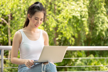 Young beautiful happy woman using laptop while relaxing in a park