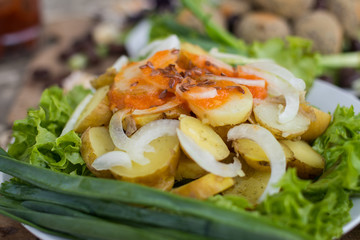 Backed, stewed new potato with onion rings, homemade tomatoes ketchup sauce on green salad leaves and onion. Raw vegan vegetarian healthy food