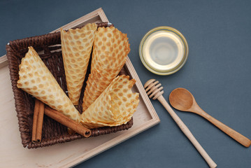 Empty waffle cones Homemade Dessert with wooden Accesories and honney. Blue Background. Top view
