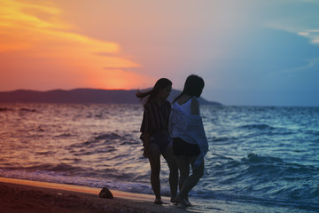 happy friend sisters with the sunset on the beach