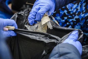 Young woman holding trash with plastic gloves.