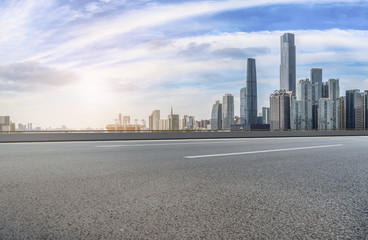 The empty asphalt road is built along modern commercial buildings in China's cities.