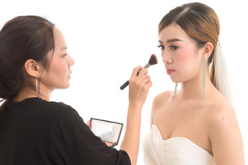 Close up makeup artist preparing asian beautiful bride before the wedding in a morning on white background.