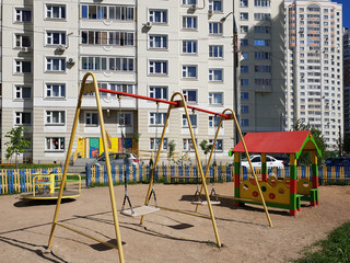 Fototapeta premium children's playground with swings in courtyard of residential building in the city, Russia