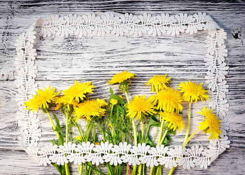 bouquet of wildflowers, dandelions and buttercups, in the style of a rustic postcard on a wooden background in a picture frame made of lace. copy space for your greeting text.