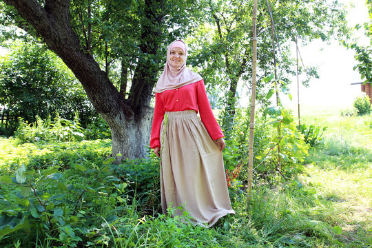 young smiling woman in colorful muslim clothes is posing in front of camera in nature