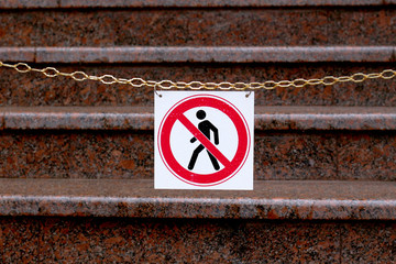 road sign prohibiting the movement of pedestrians is hanging on a chain above the stairs