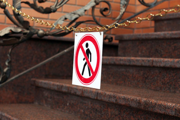 road sign prohibiting the movement of pedestrians is hanging on a chain above the stairs