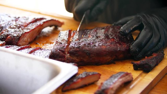 Close-up of cutting juicy ribs by a BBQ master.