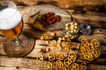 Lager beer mug and snacks on wooden table. Nuts, chips. Top view with copyspace
