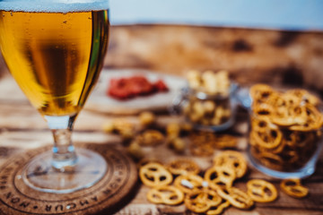 Lager beer mug and snacks on wooden table. Nuts, chips. Top view with copyspace
