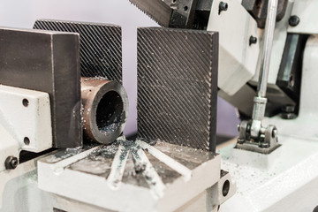 Automatic bandsaw sawing metal workpiece.