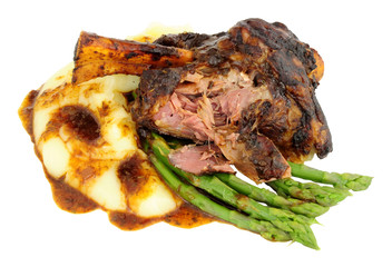 Slow cooked lamb shank meal with creamy mashed potato and asparagus isolated on a white background