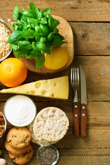 Healthy breakfast ingredients, food frame. Granola, egg, nuts, fruits, berries, toast, milk, yogurt, orange juice, cheese, banana, apple on wooden rustic background, top view, copy space.