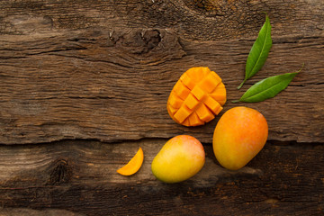 Mango fruit with slice cut and leaf on wooden background, top view. tropical fruits mango on wooden...