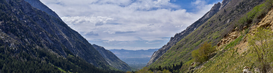 Obraz na płótnie Canvas Panoramic Views of Wasatch Front Rocky Mountains from Little Cottonwood Canyon looking towards the Great Salt Lake Valley in early spring with melting snow, pine trees and budding Quaking Aspen in Uta