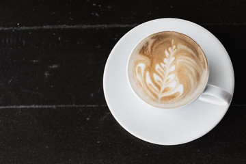 A cup of coffee in a white cup on wooden background
