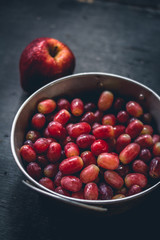 Apples and red grapes on black wood flooring in low light 